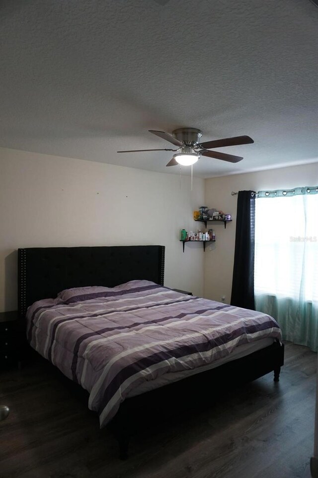 bedroom with a textured ceiling, a ceiling fan, and wood finished floors