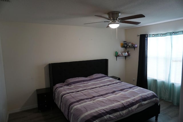 bedroom with ceiling fan, wood finished floors, visible vents, and baseboards