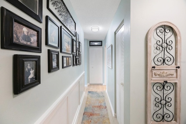 corridor featuring a textured ceiling and baseboards