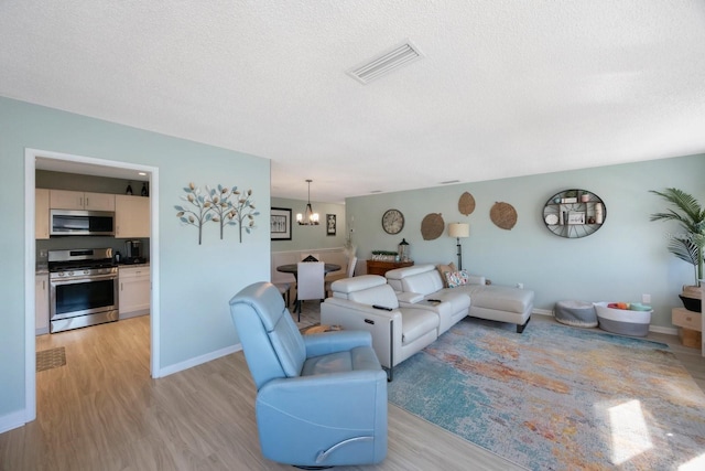 living area with light wood-style floors, visible vents, and a textured ceiling