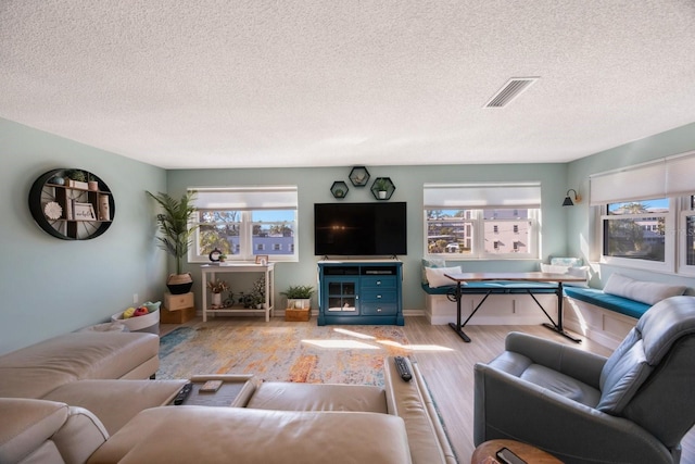 living room with light wood-style floors, visible vents, and a textured ceiling