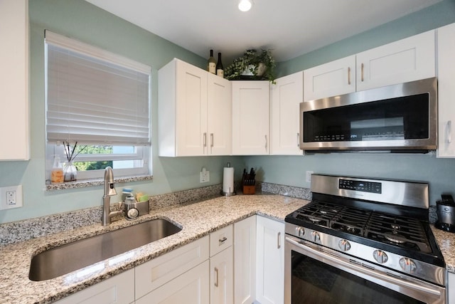 kitchen with recessed lighting, appliances with stainless steel finishes, white cabinetry, a sink, and light stone countertops