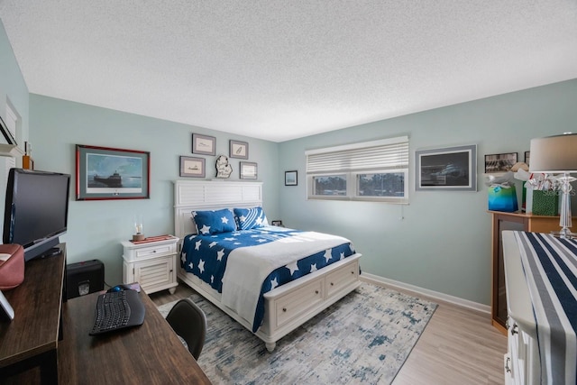 bedroom featuring light wood-style flooring, baseboards, and a textured ceiling