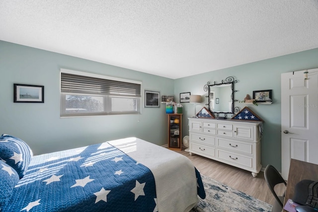 bedroom with light wood finished floors and a textured ceiling