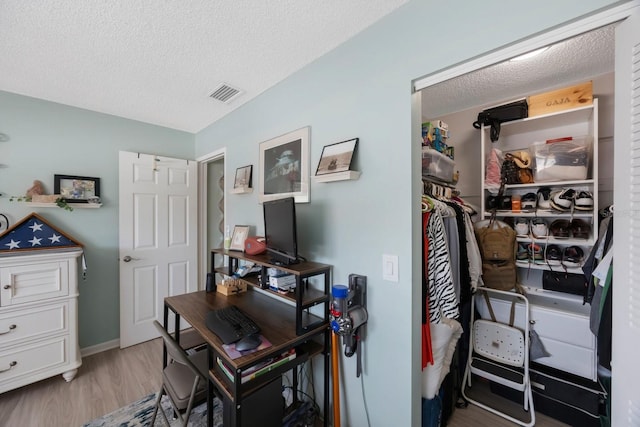 office area featuring visible vents, a textured ceiling, baseboards, and wood finished floors