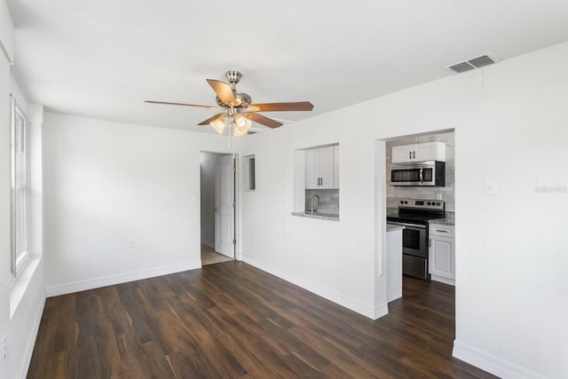 spare room with dark wood-type flooring, a sink, visible vents, baseboards, and a ceiling fan