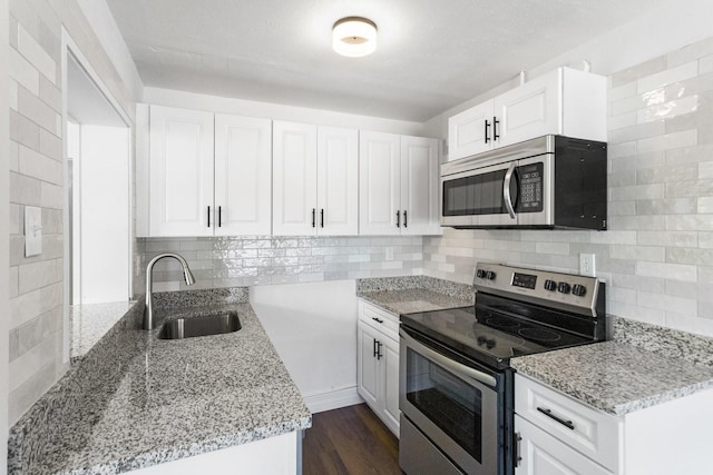 kitchen with light stone counters, a sink, white cabinetry, appliances with stainless steel finishes, and tasteful backsplash