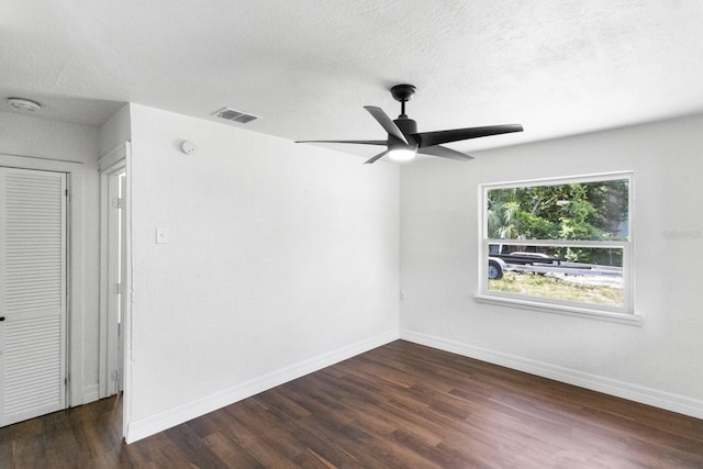 spare room featuring dark wood-style flooring, visible vents, a textured ceiling, and baseboards