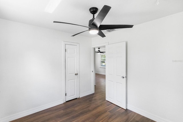 unfurnished bedroom with dark wood-type flooring, a ceiling fan, visible vents, and baseboards