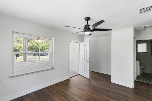 unfurnished bedroom with dark wood-style floors, ceiling fan, visible vents, and baseboards