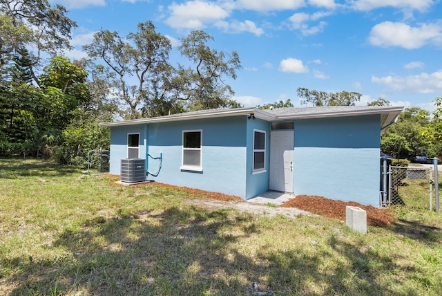 back of house featuring fence, a lawn, cooling unit, and stucco siding