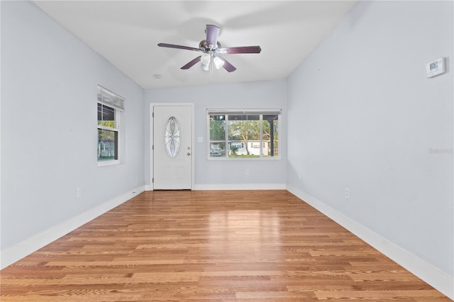 foyer with ceiling fan, baseboards, lofted ceiling, and light wood-style floors