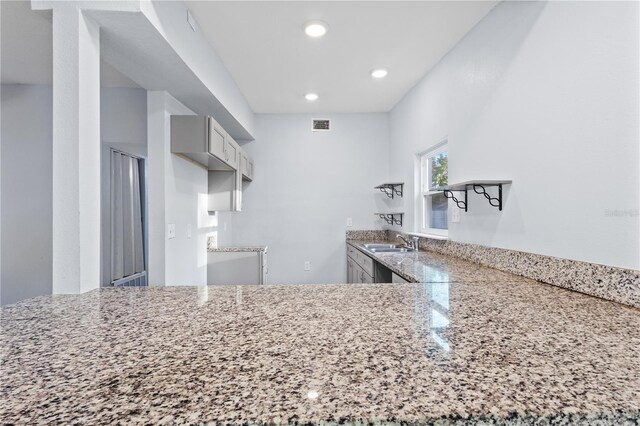 kitchen with visible vents, recessed lighting, light stone countertops, and a sink