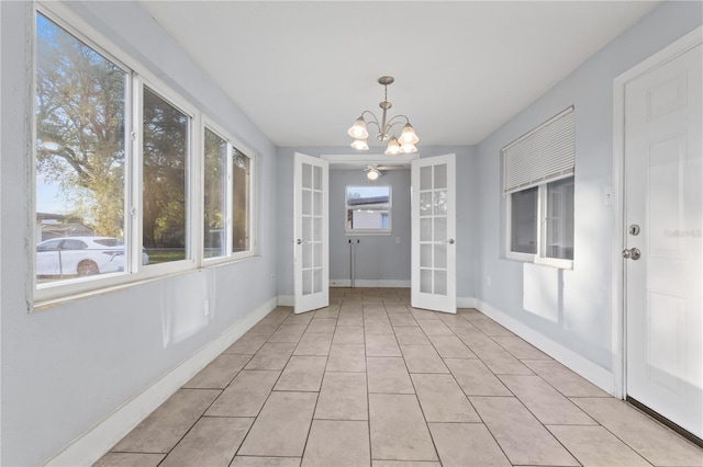 unfurnished dining area with a notable chandelier, french doors, baseboards, and light tile patterned floors