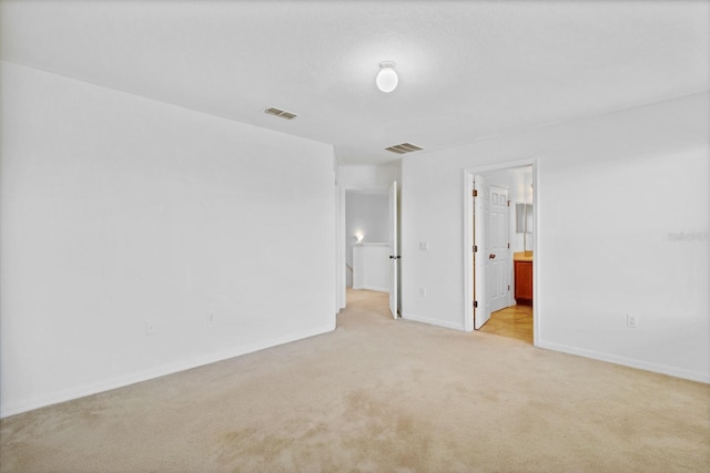 empty room with light carpet, visible vents, and baseboards