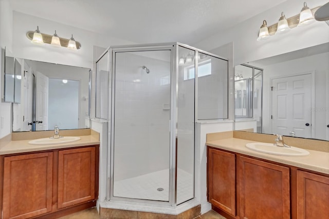 bathroom featuring a shower stall, two vanities, and a sink