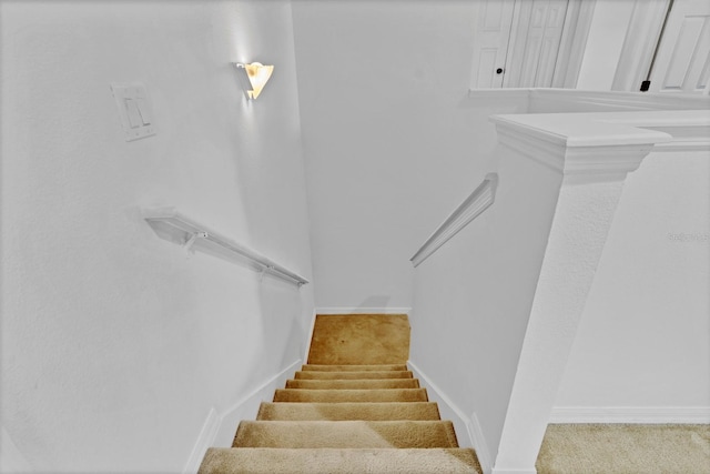 staircase featuring baseboards and carpet flooring