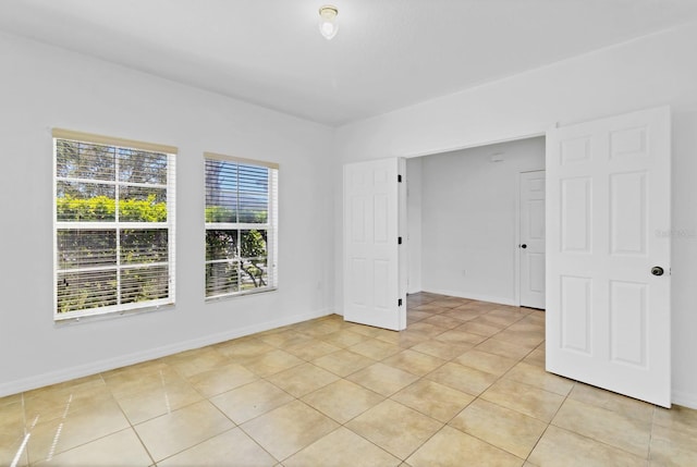 empty room featuring light tile patterned floors and baseboards