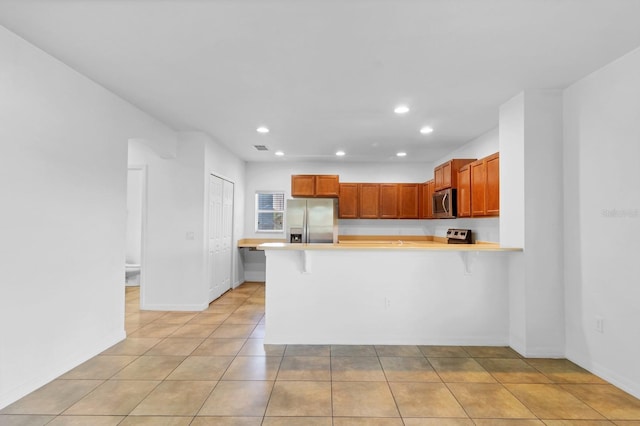 kitchen with stainless steel appliances, a peninsula, light countertops, and recessed lighting