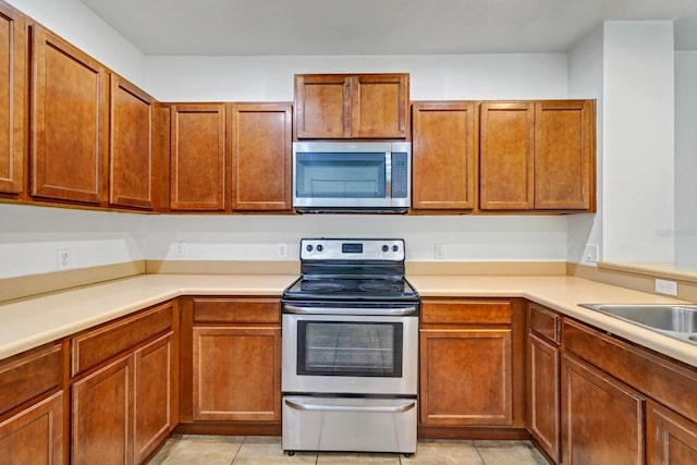 kitchen featuring light tile patterned floors, stainless steel appliances, and light countertops