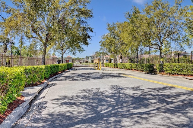 view of street with curbs, a gated entry, and a gate