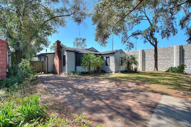 view of front of home featuring a front yard, fence, and a chimney