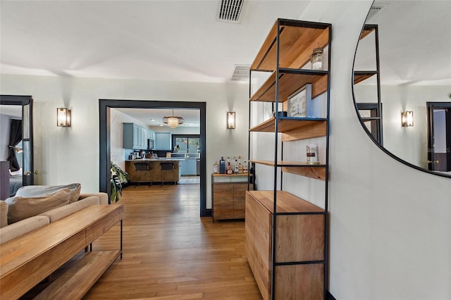 hall featuring wood finished floors and visible vents