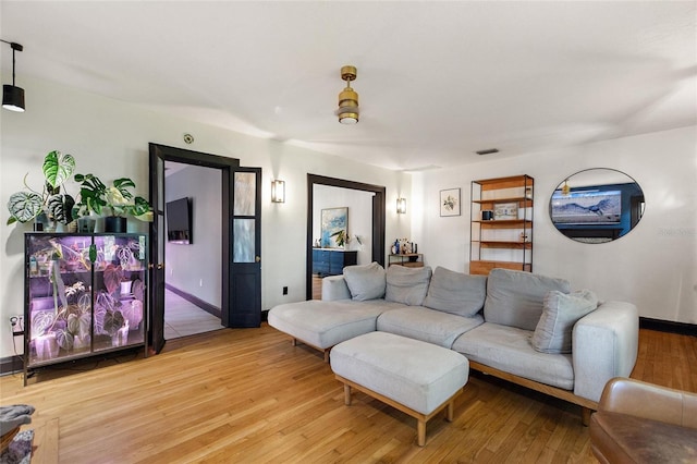 living area with light wood-style floors, visible vents, and baseboards