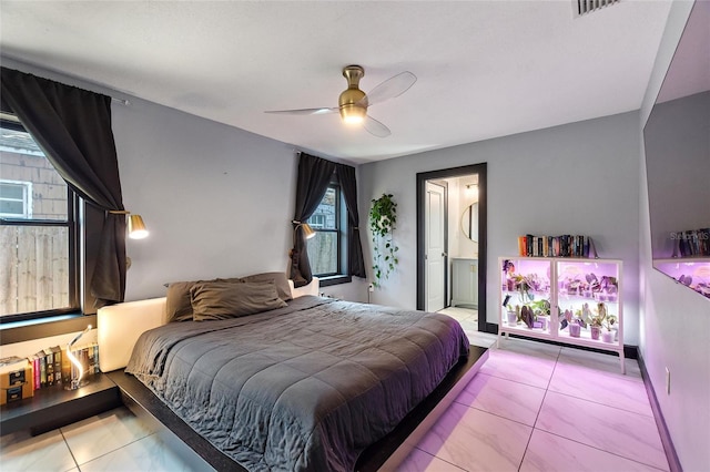 bedroom with ensuite bathroom, tile patterned flooring, and a ceiling fan