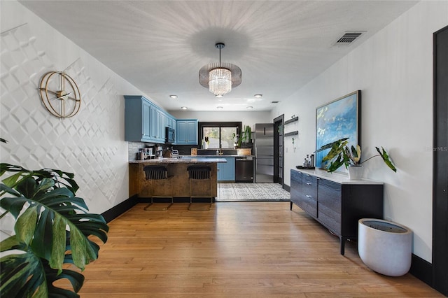 kitchen with blue cabinetry, visible vents, appliances with stainless steel finishes, light wood-type flooring, and a peninsula