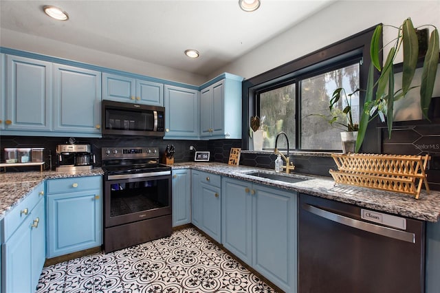 kitchen with stainless steel appliances, blue cabinets, a sink, and decorative backsplash