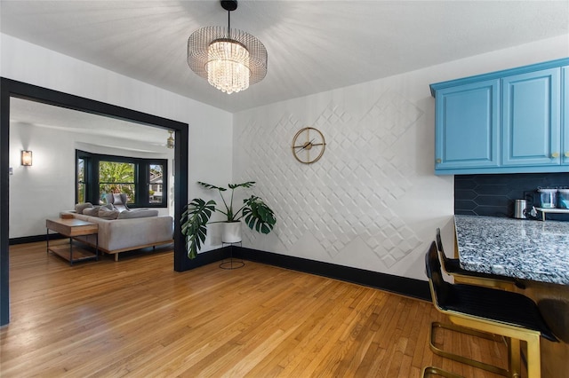 dining area featuring light wood-type flooring, a notable chandelier, and baseboards