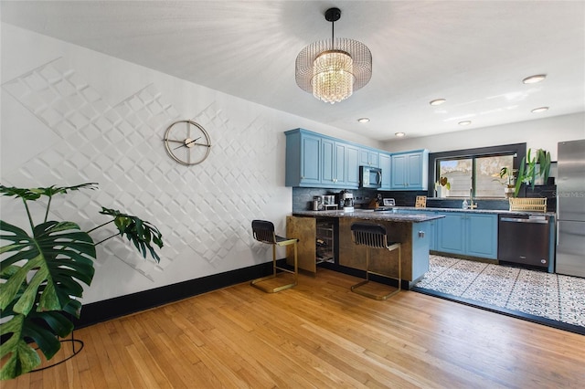 kitchen with light wood-type flooring, blue cabinetry, a peninsula, and stainless steel appliances