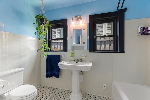 full bathroom featuring toilet, tile walls, and a bath