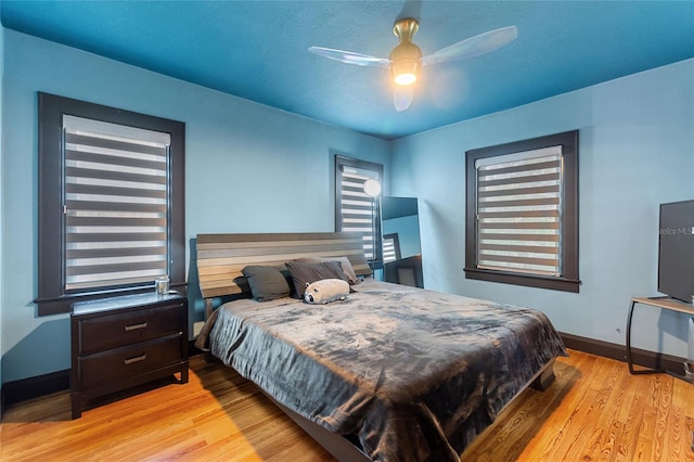 bedroom featuring a ceiling fan, baseboards, and wood finished floors