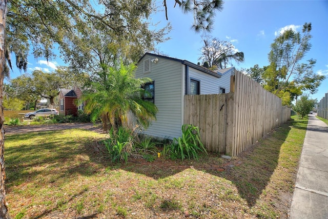 view of side of home with fence and a yard