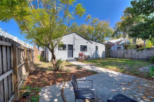 exterior space with central air condition unit, a fenced backyard, a lawn, and a patio