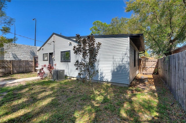 back of house featuring a fenced backyard, central AC, and a yard