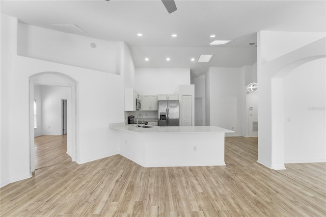 kitchen with arched walkways, stainless steel appliances, light countertops, a sink, and a peninsula