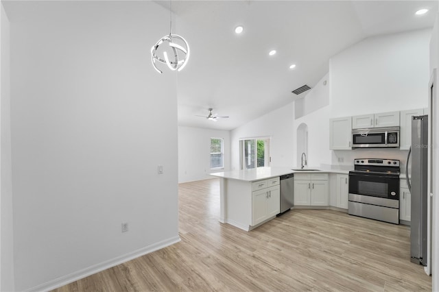 kitchen featuring a peninsula, a sink, open floor plan, appliances with stainless steel finishes, and light wood finished floors