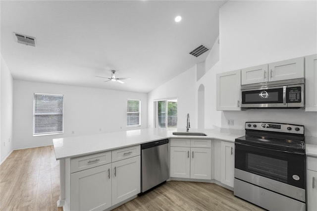 kitchen with a peninsula, a sink, visible vents, light countertops, and appliances with stainless steel finishes