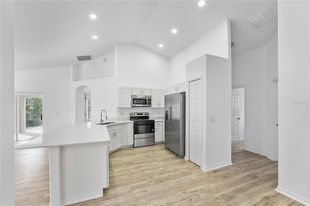 kitchen with arched walkways, stainless steel appliances, a peninsula, visible vents, and light wood-style floors