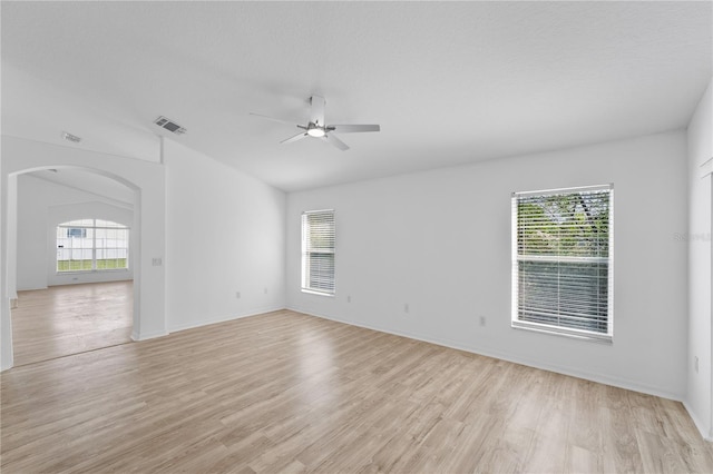 spare room featuring a ceiling fan, arched walkways, visible vents, and light wood finished floors