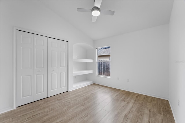 unfurnished bedroom with baseboards, lofted ceiling, ceiling fan, light wood-type flooring, and a closet