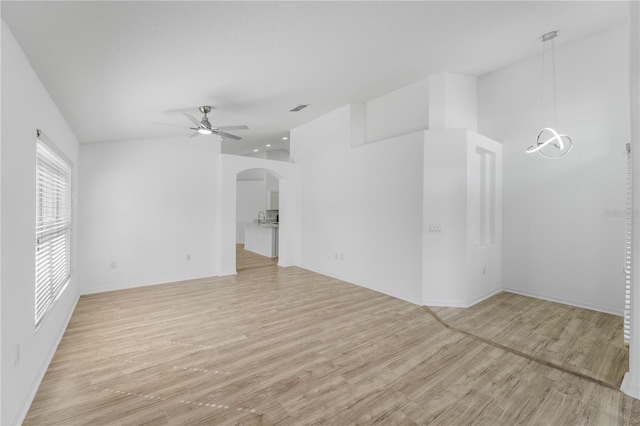 spare room with light wood finished floors, visible vents, arched walkways, a sink, and ceiling fan with notable chandelier