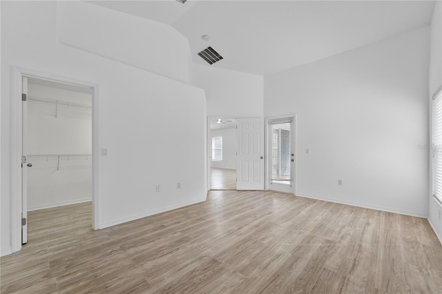 unfurnished room featuring lofted ceiling, light wood finished floors, visible vents, and baseboards