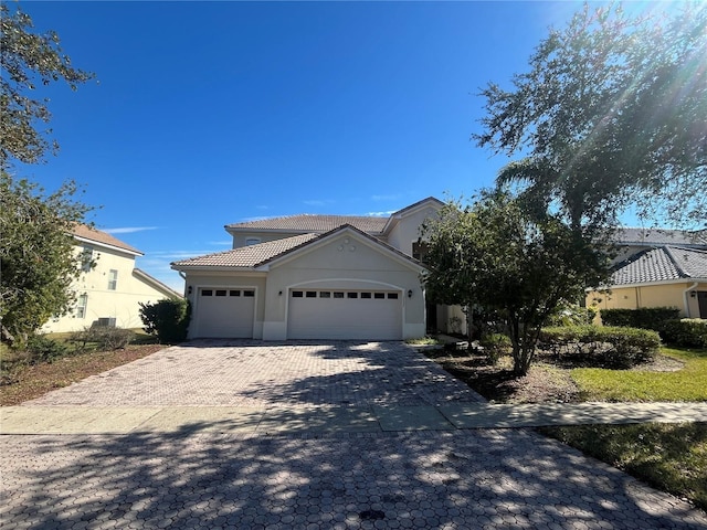 view of front of home featuring a garage, decorative driveway, stucco siding, and a tile roof