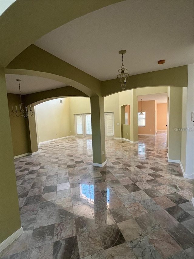 spare room with baseboards, arched walkways, and a healthy amount of sunlight