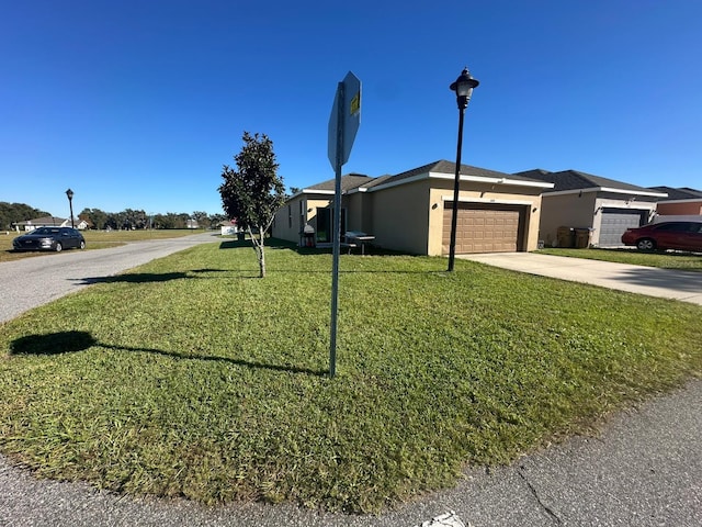 view of front of property with a garage, stucco siding, concrete driveway, and a front yard