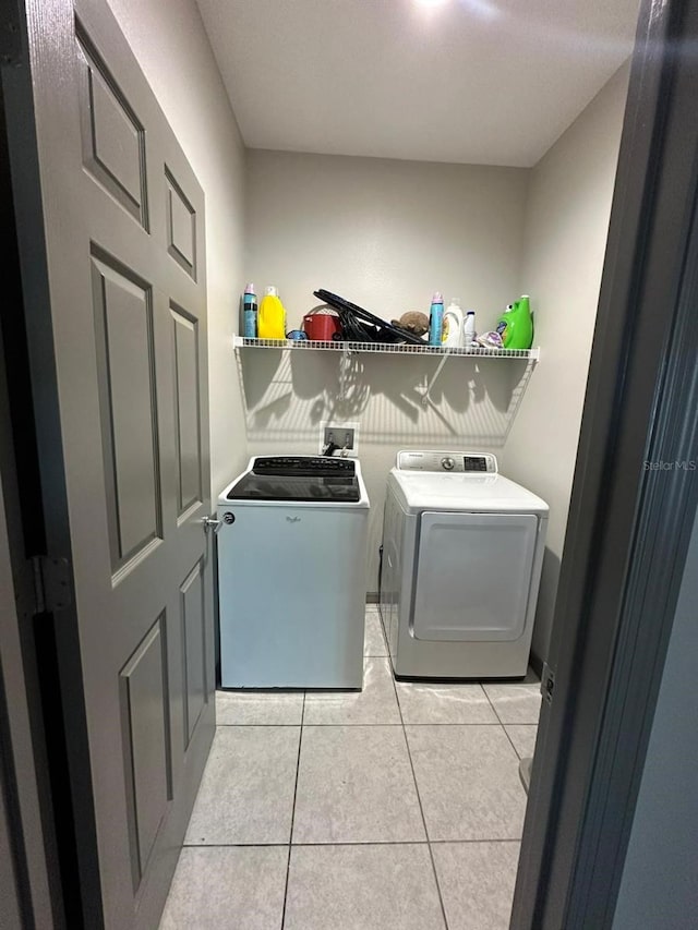 laundry room featuring laundry area, washing machine and dryer, and light tile patterned flooring